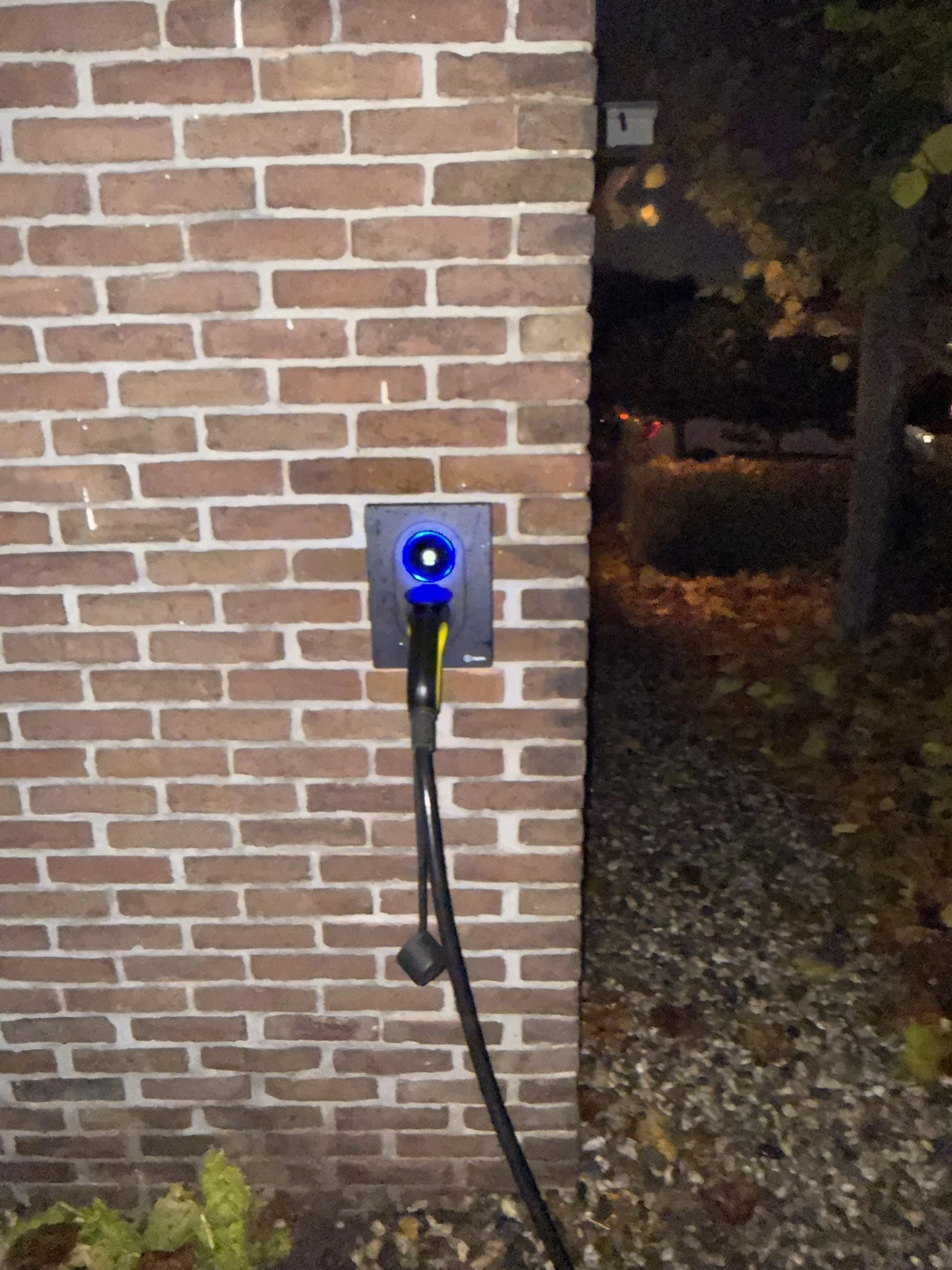 Zaptec laadpaal met blauwe ring aan een bakstenen gevel in Hellevoetsluis